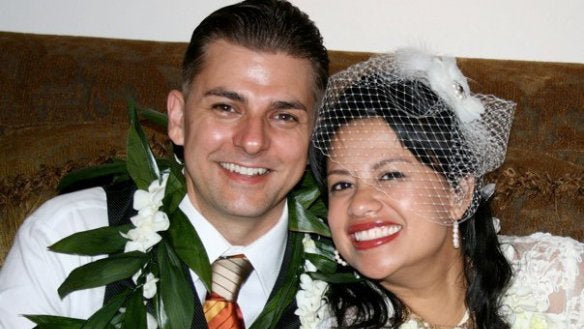 Man and woman on a wedding day, smiling at the camera.